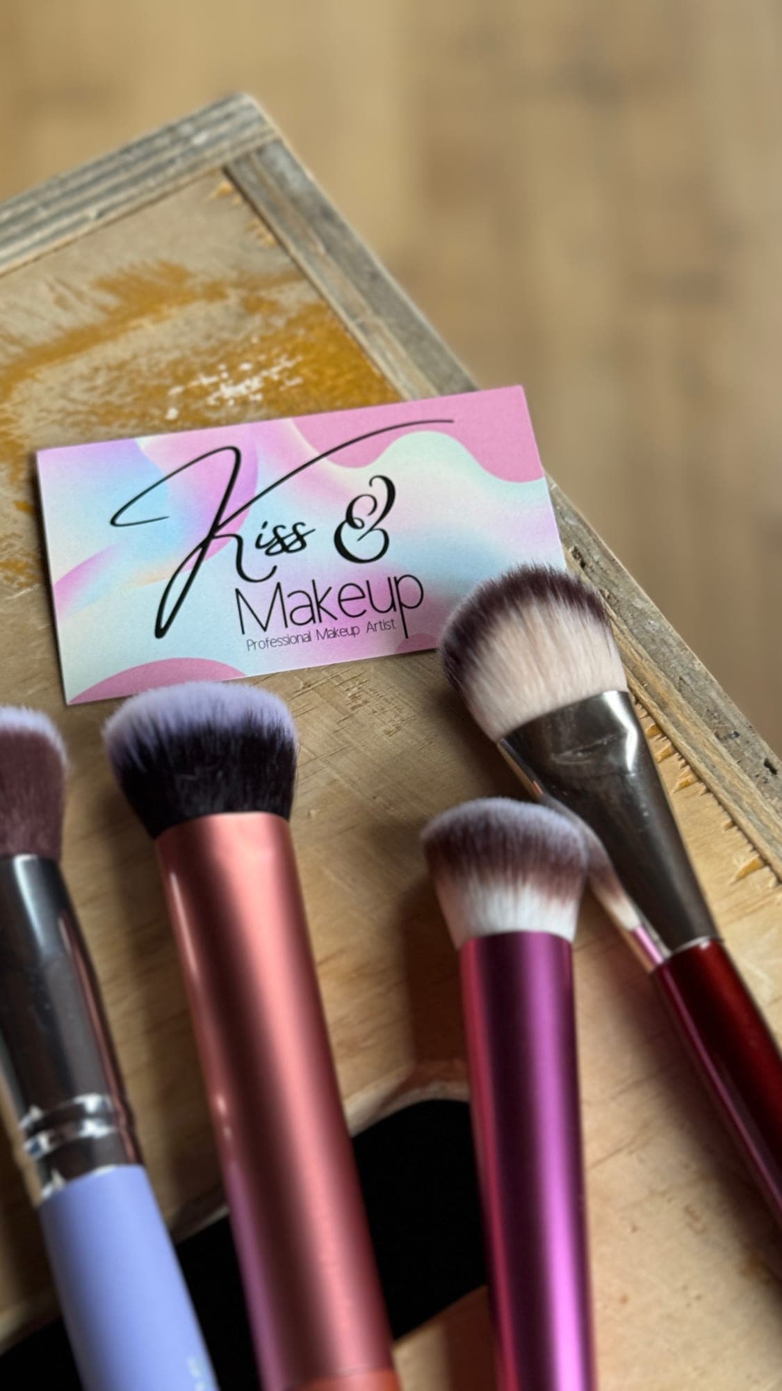 Makeup brushes laid out beside a Kiss & Makeup business card