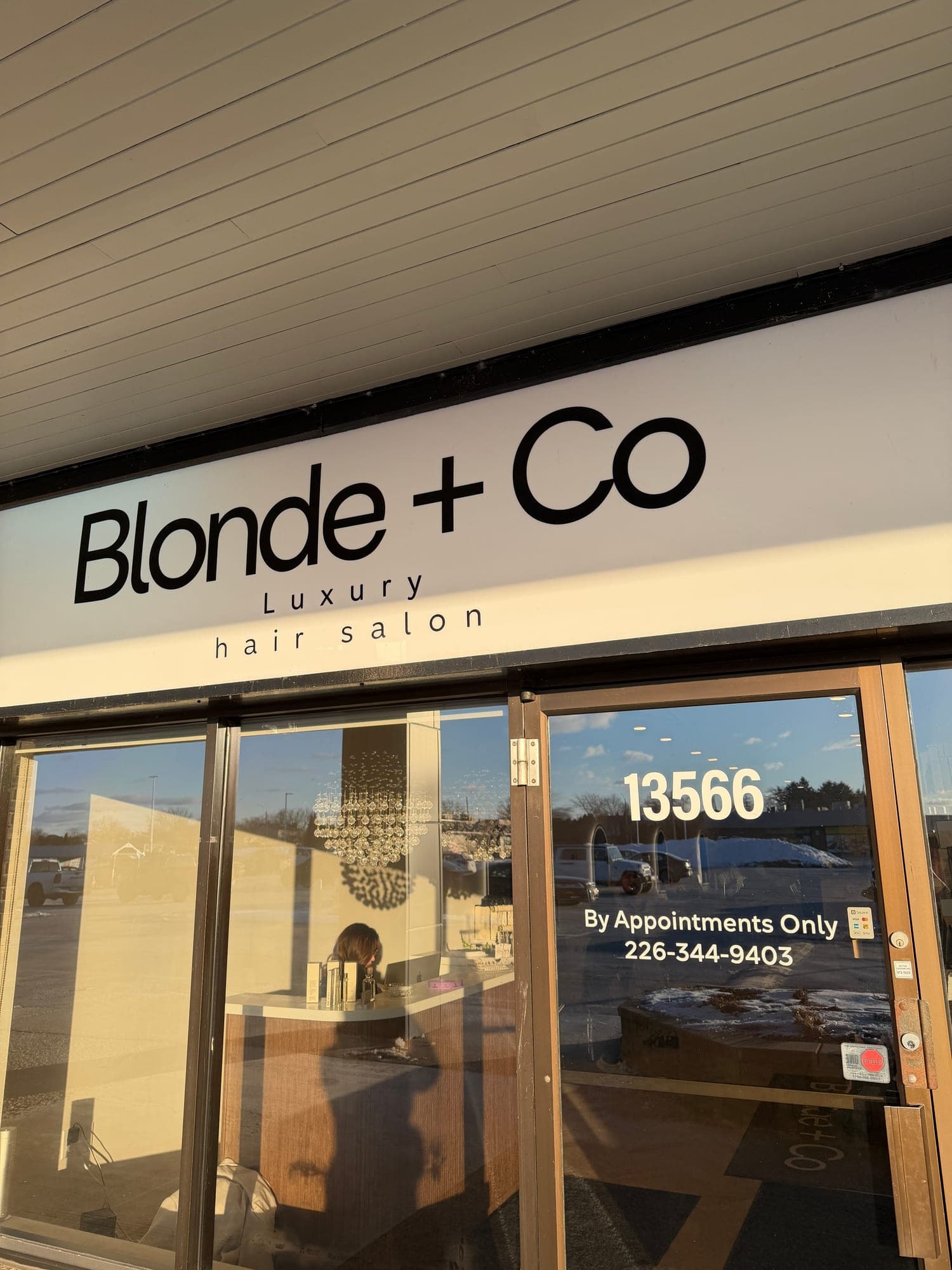 The Blonde + Co salon sign lit by late afternoon sun