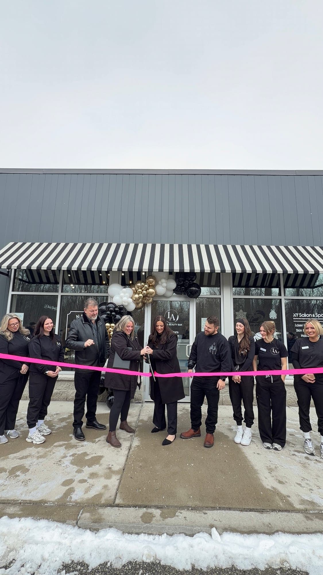 The LA Nails team cutting a pink ribbon outside their new salon