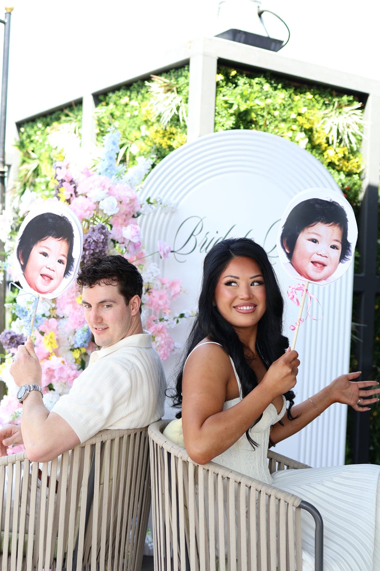 A couple playing a guess-who game with baby photo cutouts at their shower